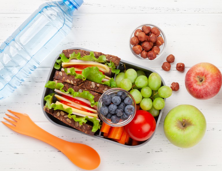 Healthy school lunch box with sandwich and fresh vegetables Healthy school lunch box with sandwich and fresh vegetables, water bottle, nuts and fruits. Top view flat lay